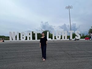 a woman standing in front of a large sign at Night Lights Festival