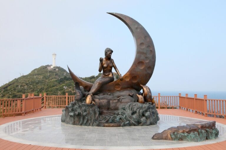 Bronze mermaid statue on crescent moon.